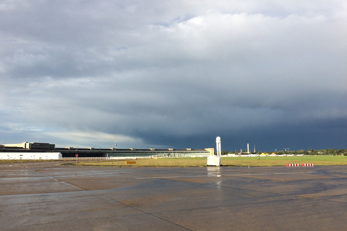 Eine Abbildung des alten Flughafen Tempelhof, das Bild ist Hell und Dunkeln. Der Himmel ist bedeckt und der Piste ist fast weiss von der Sonnestrahlung